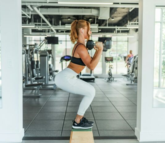건강한 다리 근육을 위한 운동 woman wearing black sports bra and white legging lifting dummbells