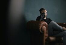 스트레스가 건강에 미치는 영향과 회복 방법 a man holds his head while sitting on a sofa