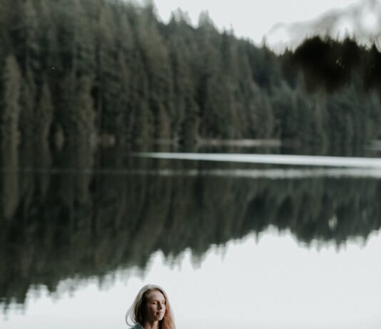 겨울철 다이어트 성공을 위한 심리 관리 woman meditating on rock in bank of lake