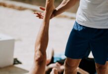 겨울철 숙면을 돕는 요가 자세 man lying on floor near man standing holding his leg