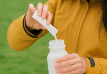 “영양, 식탁 만족에서 시작”… 보충제 현명하게 활용하는 생활 습관 Person pouring powder into a water bottle