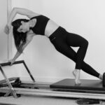 필라테스와 숙면: “밤마다 뒤척인다면?” 불면증을 해소하고 수면의 질을 높이는 저녁 루틴 woman in black sports bra and black leggings doing yoga