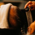 “건강한 모발 관리, 일상 속 작은 습관에서 시작하세요” a man getting his hair washed in a sink