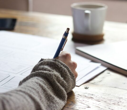 일상에서 실천하는 웰니스 문화, 작은 변화가 건강을 부른다 person writing on brown wooden table near white ceramic mug