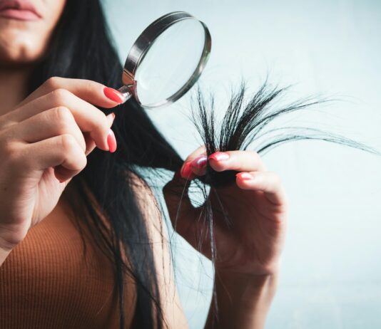 최신 ‘헤어 헬스’ 트렌드, 집에서 실천하는 건강한 머릿결 관리법 Woman examining split ends of hair with magnifying glass