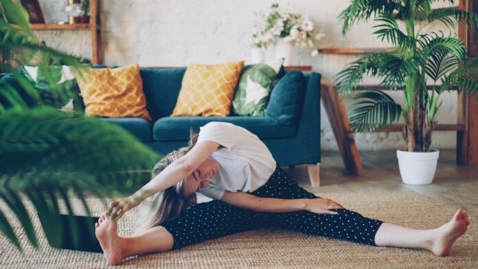Photo by Vitaly Gariev Woman stretching on floor in a living room.
