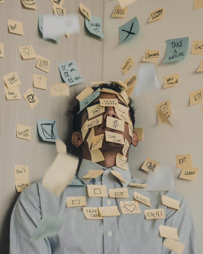 man covered in sticky notes at office desk
