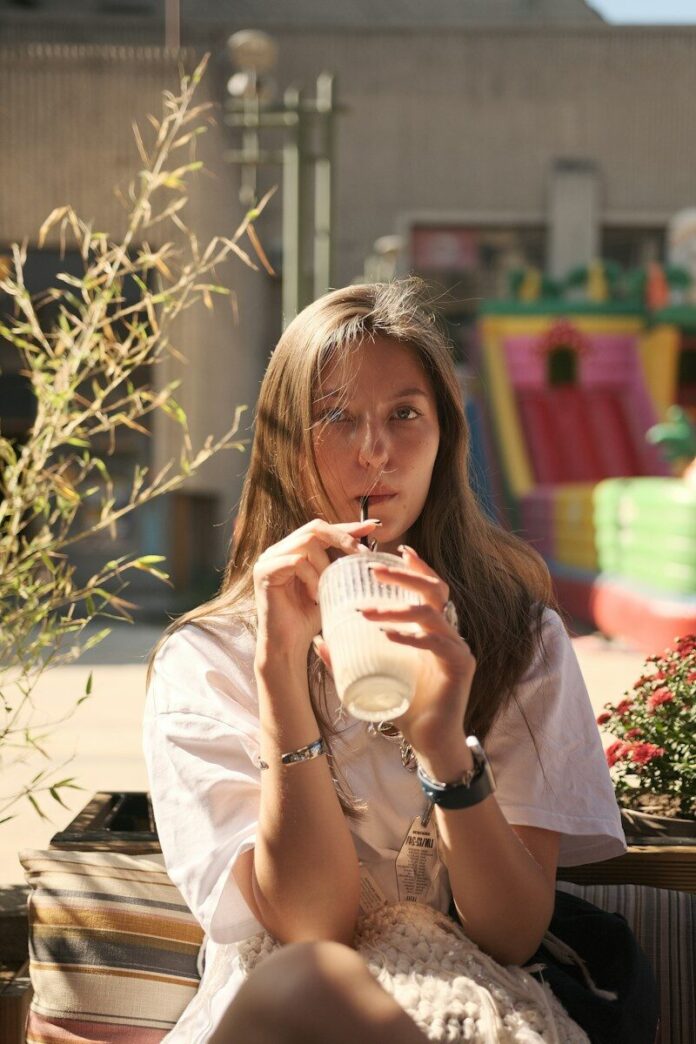 Woman sips a drink on a sunny outdoor patio